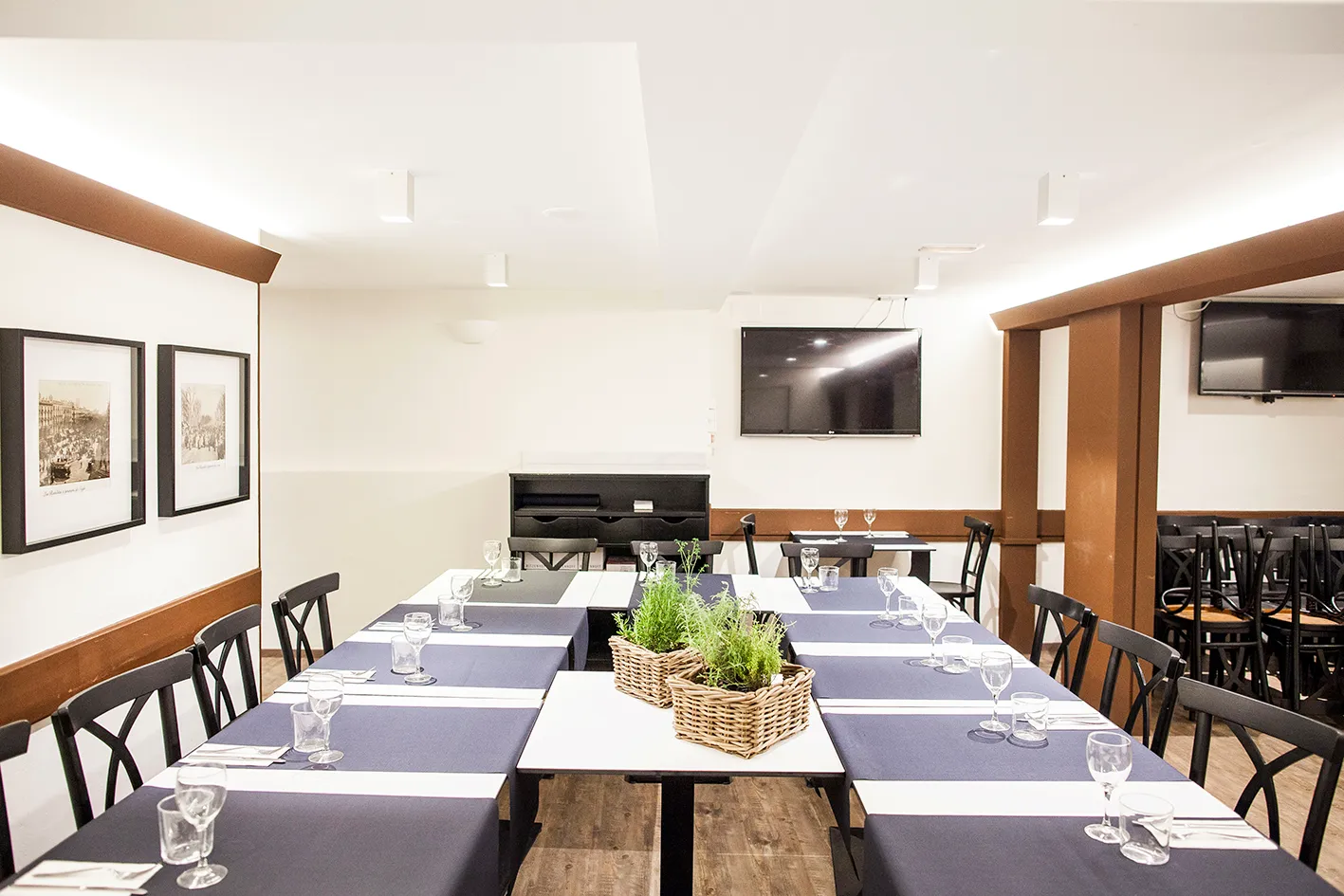 Mesas juntas montadas para una cena de grupo en Santa Anna, con copas y cestas de romero en el centro.
