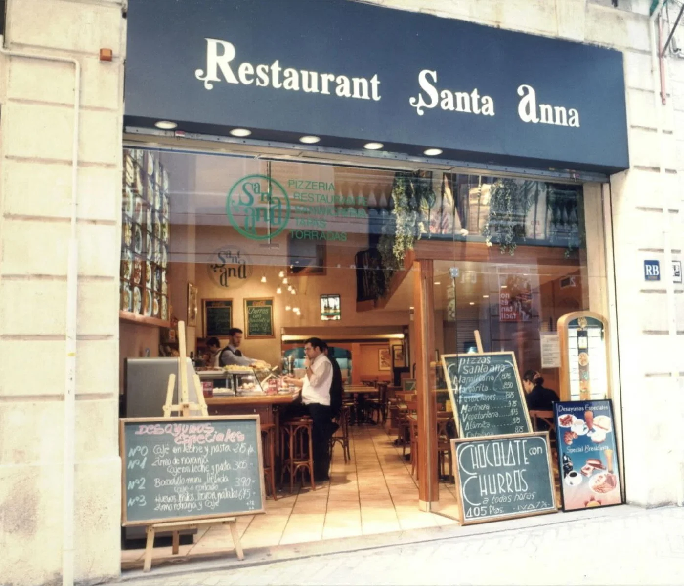 La fachada del número 8 antes de la reforma: toldo azul con el rótulo Restaurant Santa Anna y pizarras con los precios en pesetas.